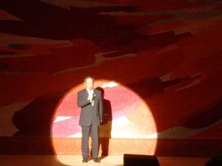 市長が舞台でライトに照らされお話ししている写真