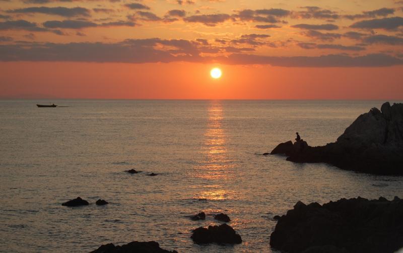 オレンジ色の空と海面に映る夕日のベールの写真