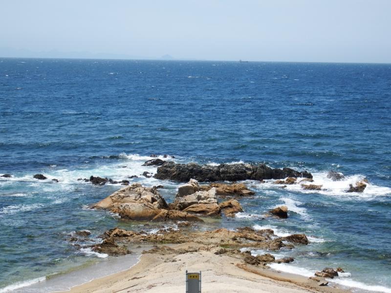 岩に打ち寄せる波で白く飛沫が立つ海の写真