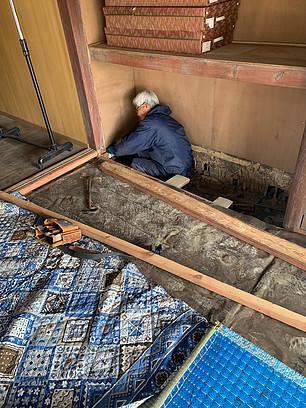 空き家の押入れスペースの床下で作業をしている男性の写真