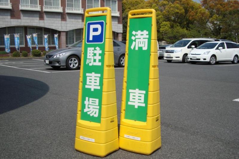 全体が黄色で緑地に白文字で左側が「駐車場」右側が「満車」と書かれた案内板の写真