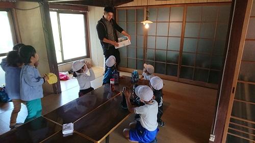 和室に並んでいる折り畳み式の長机に座って、掘ったさつまいもが配られるのを待っている子供たちの写真