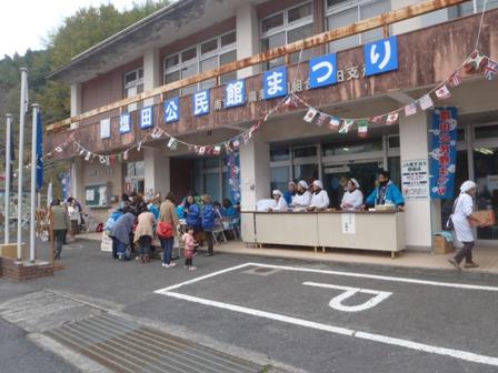 塩田公民館まつりの看板が掲げられた塩田公民館・しおたふれあいセンター入り口に集まる住民たちの写真