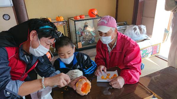 隊員と地域住民と子どもがかぼちゃランタンを作成する様子