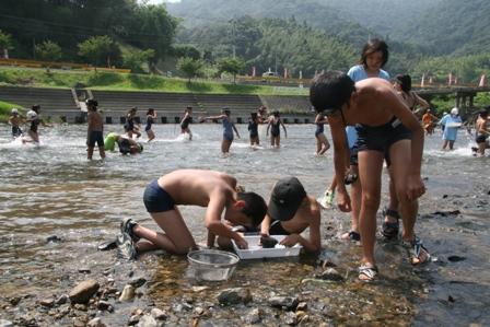 川の浅瀬で水着で遊ぶ男の子たちの写真
