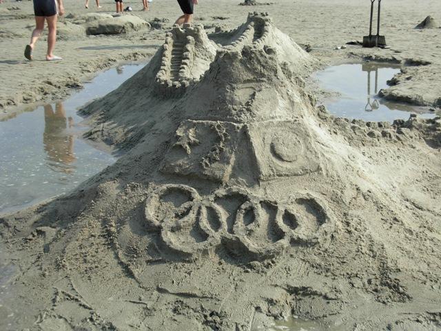 海岸で砂を積み上げたものに丸い円形を形作ったサンドアートの写真