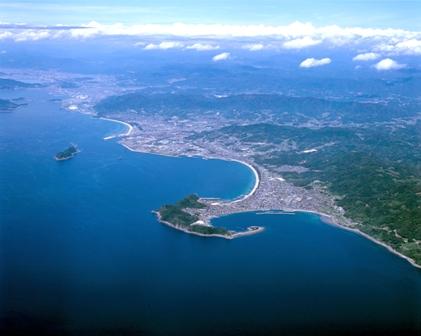 空中から海と陸地とその上にかかる雲を撮影した写真