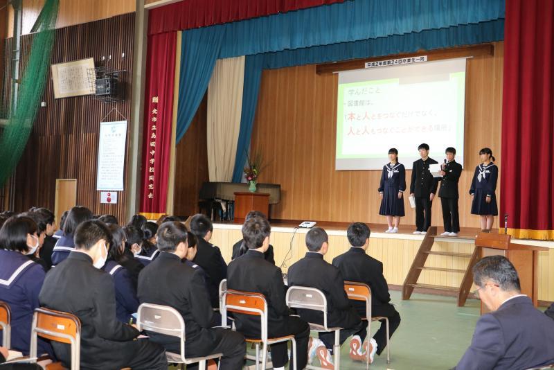 4名の学生がステージの上に立ち発表をしている写真