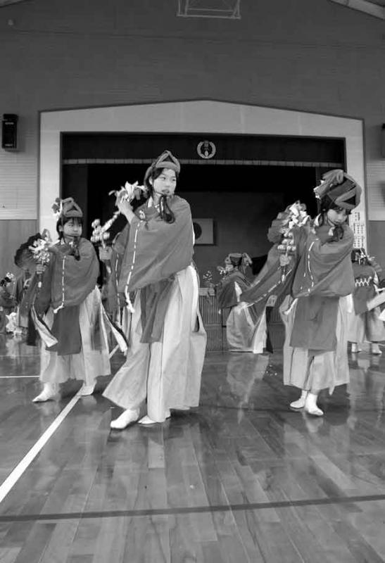 袴や烏帽子など神舞衣装に身を包んだ子どもたちが体育館で「束荷神舞」を踊っている写真