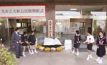 大和公民館開館式で公民館の看板の除幕を行っている制服姿の子供達5人と背広姿の男性の写真
