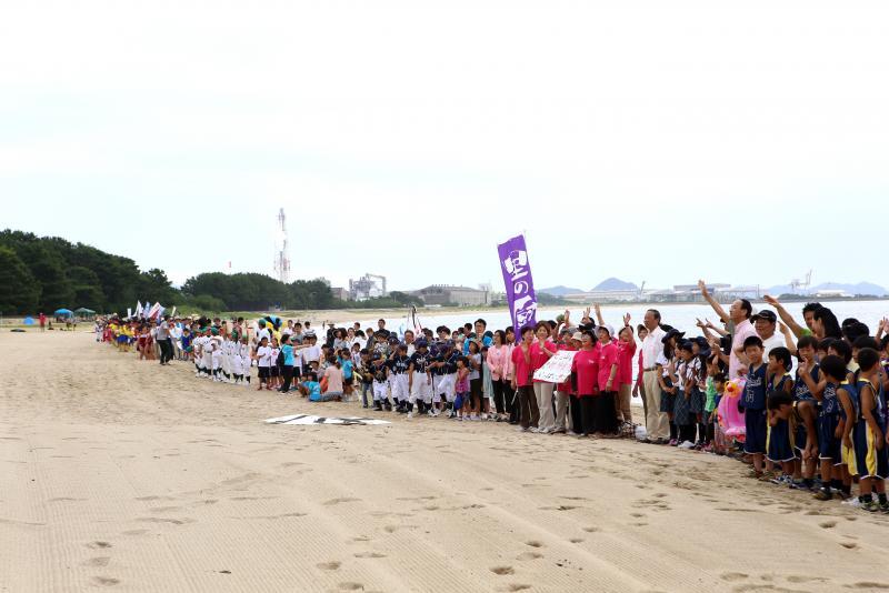 砂浜に市民が長い列を作って並んでいる写真