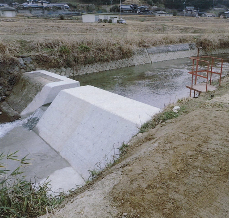 水嵩の増えた川とコンクリートで新しく作られた頭首工の写真