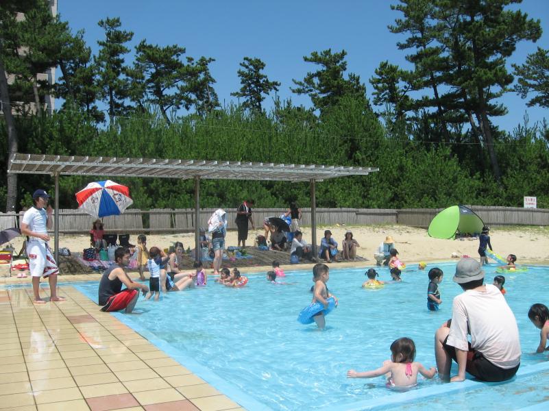虹ケ浜幼児用プールで泳ぐ子どもたちと見守る親たちの写真