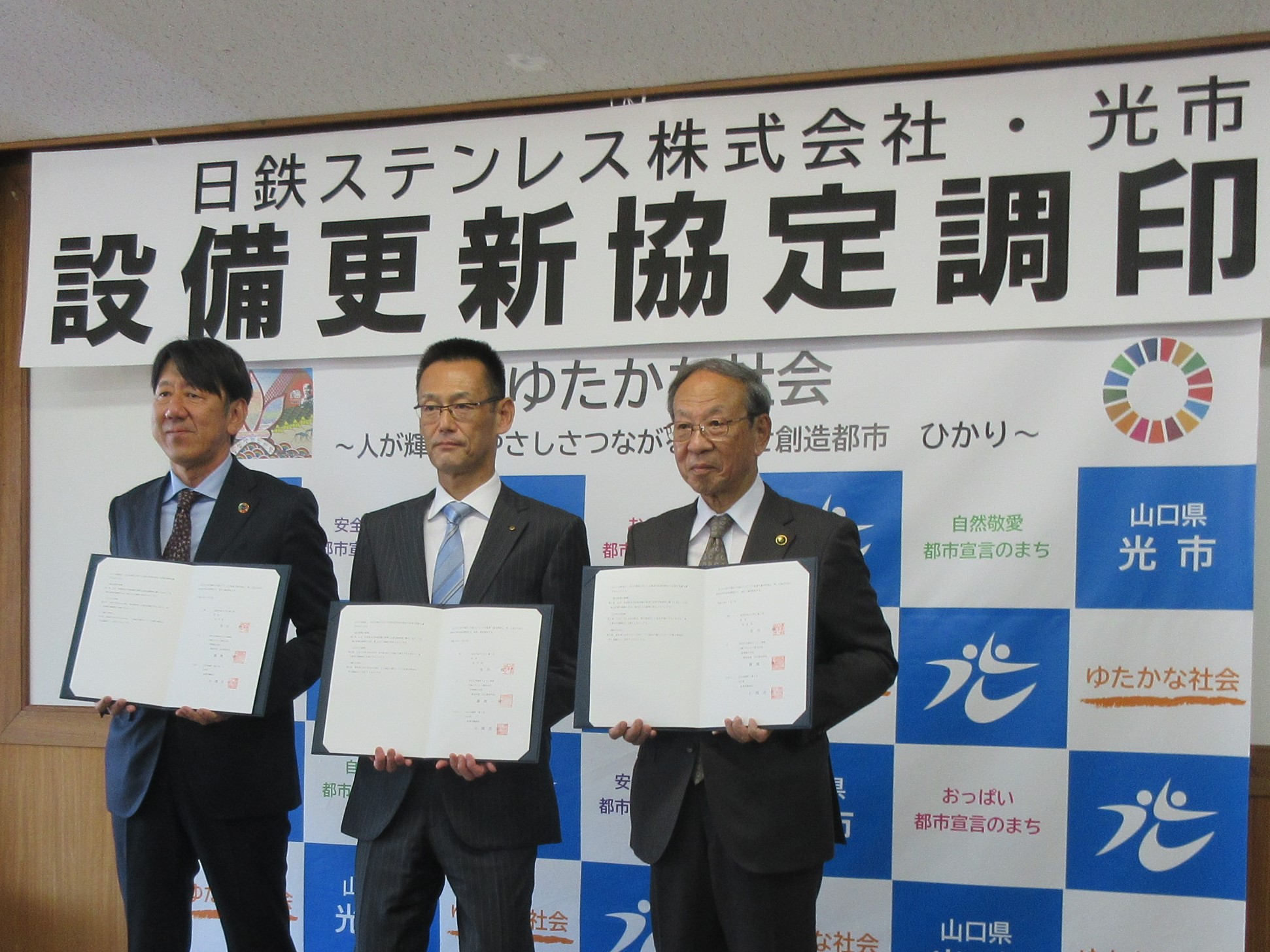 市川市長、日鉄ステンレス株式会社製造本部山口製造所の藤池所長、山口県の縄田企業立地統括監が、それぞれ調印された協定書を手に記念撮影を行っている様子