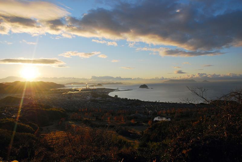 茶臼山からのぞく日の出と、街並み、右側に写る海の写真