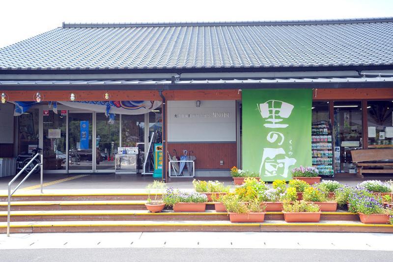 花が植えられたプランターと里の厨と書かれた緑色の看板が店の前に出ている写真
