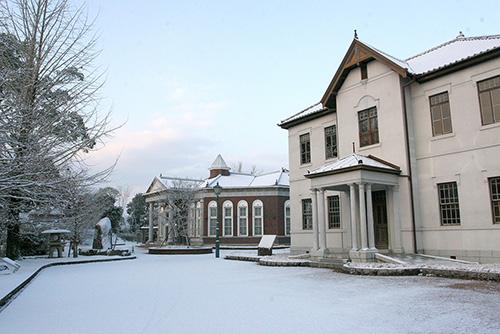 真っ白く雪化粧した旧伊藤 博文邸と樹木の写真