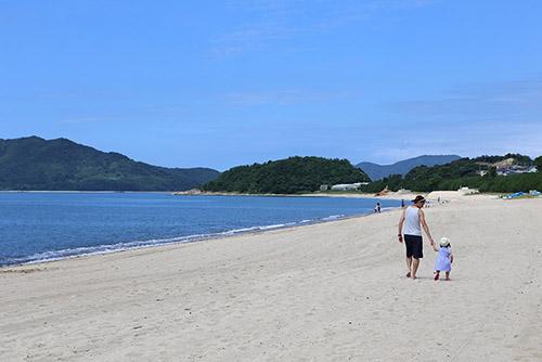 虹ケ浜海岸の砂浜を歩く親子の写真