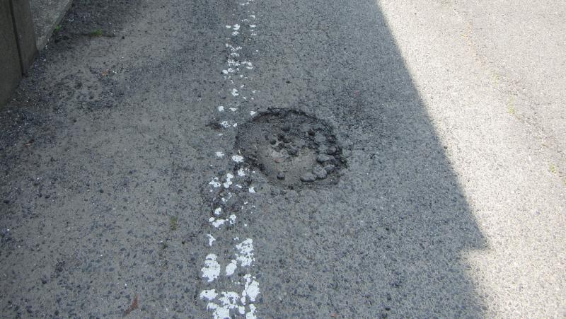 道路のアスファルトの表層がはがれてできた丸いくぼみの写真